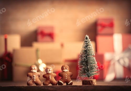 Preview: Little gingerbread man and Christmas tree on table with gifts on background