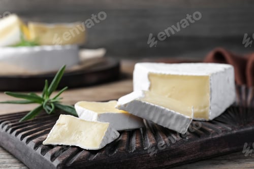 Preview: Tasty cut brie cheese with rosemary on wooden board, closeup