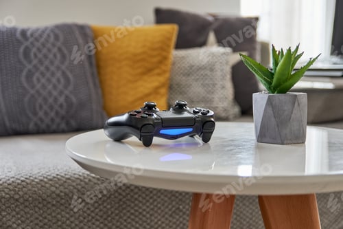 Preview: Selective focus, depth of field image of gaming controller on white table in living room.