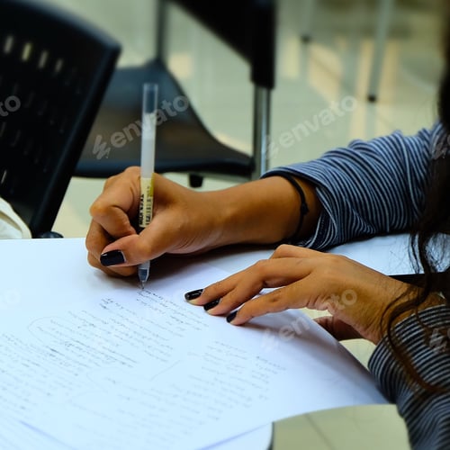 Adult Writes on Paper at Desk Indoors
