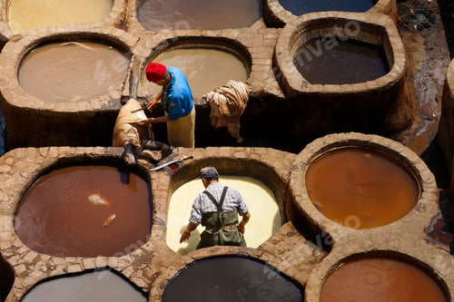 Preview: Round stone vessels with dye liquids and men working in famous Chouara Tannery