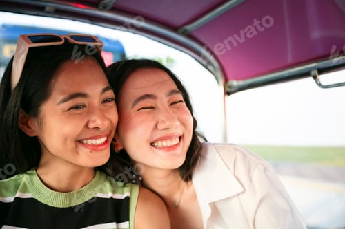 Preview: Two happy young women enjoying tuk tuk ride in thailand