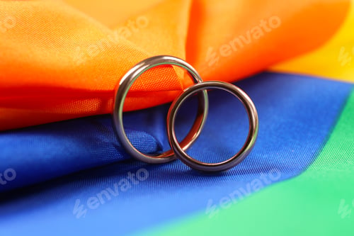 Preview: Wedding rings on rainbow LGBT flag, closeup