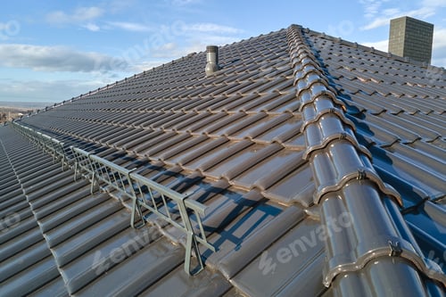 Preview: Closeup snow guard for safety in winter on house roof top covered with ceramic shingles.