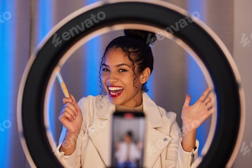 Preview: Shot of a young woman using a phone and ring light to film a makeup tutorial at home