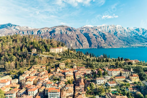 Preview: Aerial view of Bellagio village on Como lake with blue sky and the Alps in the background