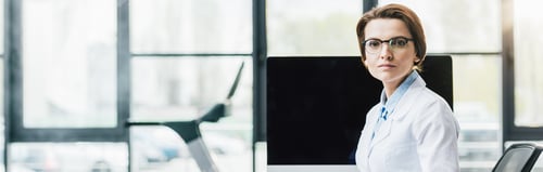 Preview: panoramic of doctor in white coat sitting at computer desk at gym