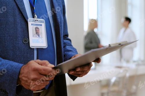Preview: Middle Aged Man Holding Clipboard in Modern Medical Office Setting