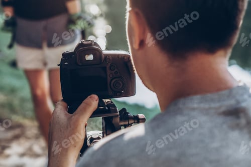 Preview: Man holding photo camera and filming footage