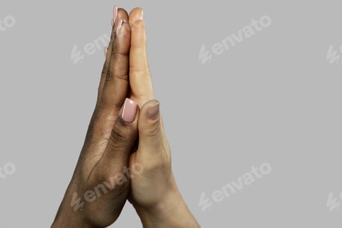 Preview: A high five gesture between African and Caucasian women. Closeup of palms on gray background.