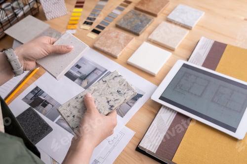 Preview: Hands of young female designer holding two samples of marble tile over table