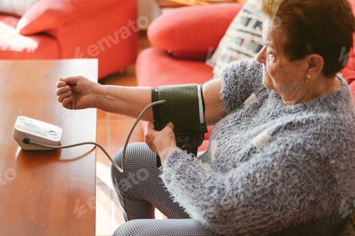 Preview: Elderly woman putting on the compression cuff of a blood pressure monitor.