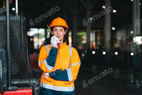 Preview: Female worker in orange safety uniform holds radio