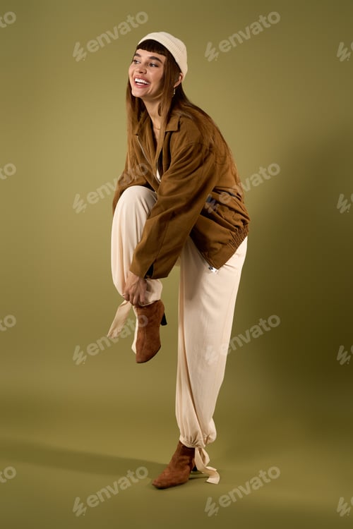 Preview: Young woman in stylish outfit enjoys playful moment with laughter in a serene green setting