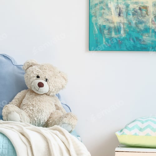Preview: Beige teddy bear on a blue bed