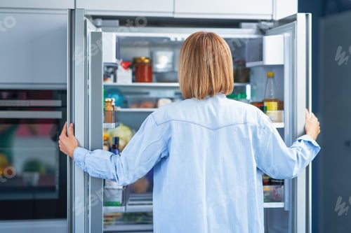 Preview: Young adult woman in the kitchen with the fridge