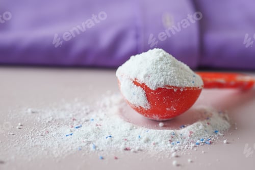 Preview: Washing powder in plastic spoon on blue background