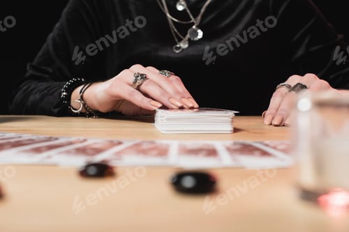 Preview: selective focus of female psychic laying tarot cards near divination stones