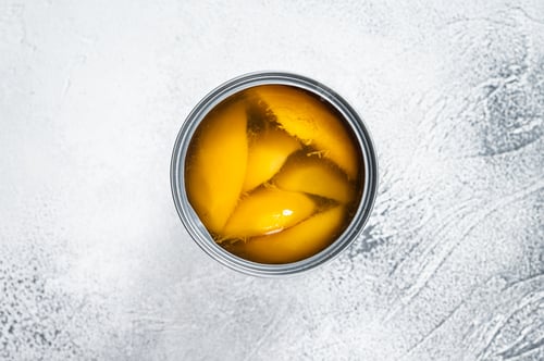 Preview: Canned mango slices in syrup in a metal can. White background. Top view