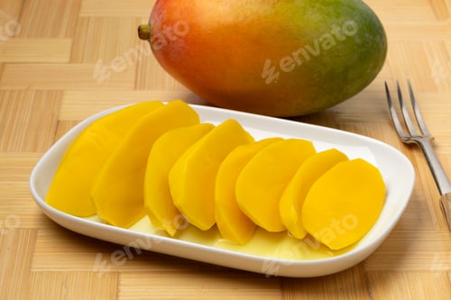 Preview: Plate with pickled mango slices and a fresh mango close up