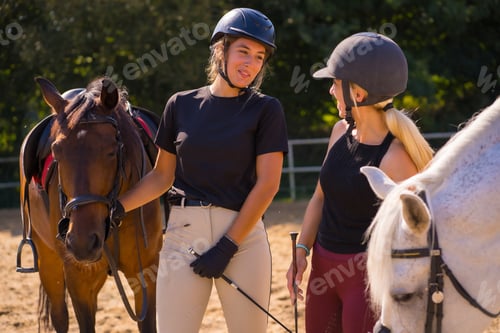 Preview: Two young Caucasian girl riders with their white and brown horses on a horse riding