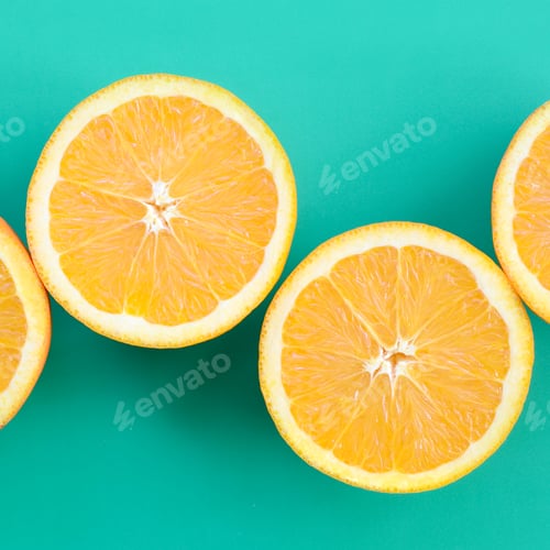 Preview: Top view of a several orange fruit slices on bright background in turquoise green color