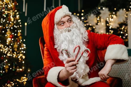 Preview: Santa claus holding candy canes near christmas tree