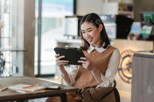 Preview: Young Asian businesswoman holding tablet concentrating on office work.