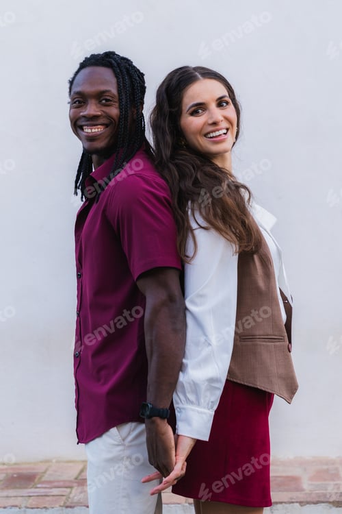 Preview: Multiracial couple smiling back to back holding hands