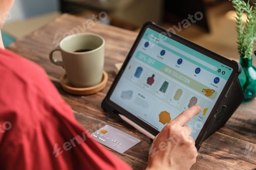 Preview: close up woman hand using credit card shopping online on mobile app on wood table at home