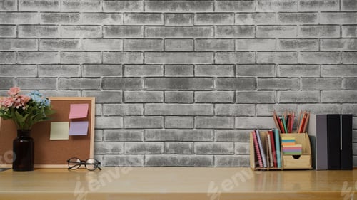 Preview: Stylish workplace with books, pencil holder and flower pot on wooden table against brick wall.