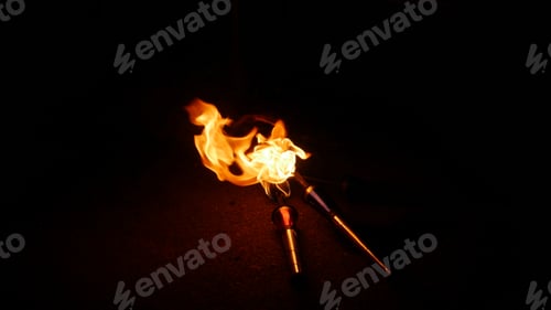 Preview: Closeup shot of two burning juggling torches on a dark background