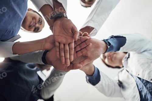 Preview: We can do this guys. Shot of a group of young doctors and n nurses with their hands stacked.