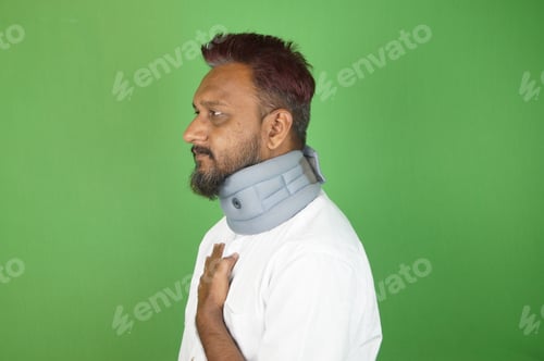 Preview: Indian adult man damaged his neck and standing with a neck warmer on the green background