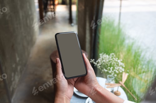 Preview: Mockup image of a woman holding mobile phone with blank desktop screen in cafe