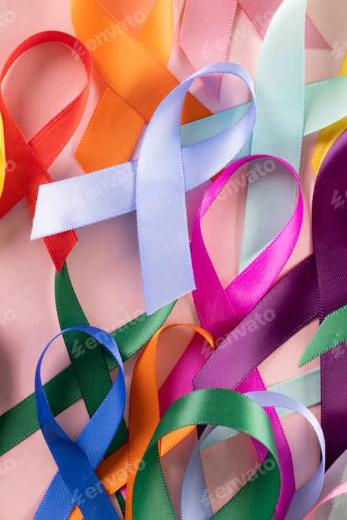 Preview: Extreme close-up of various multicolored awareness ribbons over pink background, copy space