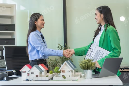 Preview: Two businesswomen sit at a table in the office,discussing a model village with windmills