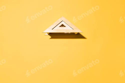 Preview: Toy wooden roof on yellow background top view, copy space. Housing concept, insurance, ad space