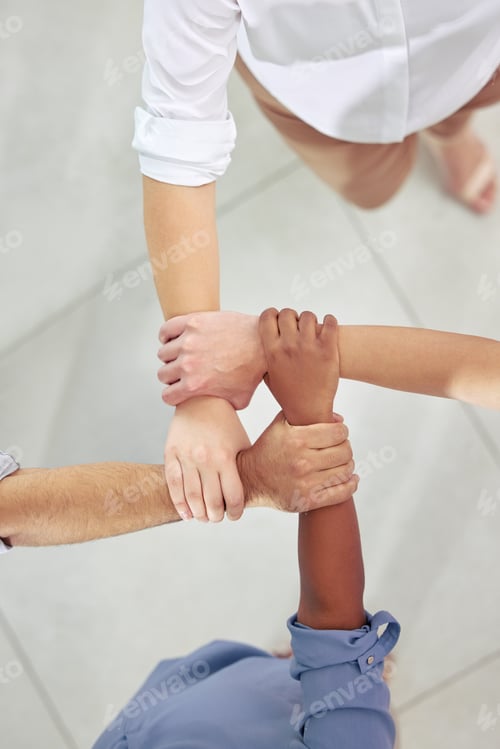 Preview: High angle shot of a group of unrecognizable businesspeople holding on to each others arms at work