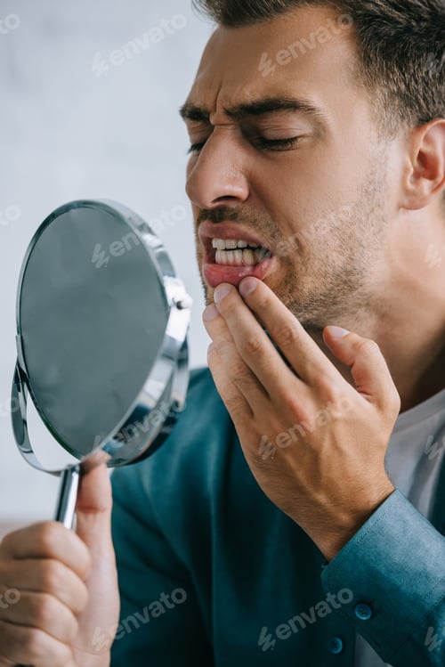 Preview: young man with toothache looking at mirror
