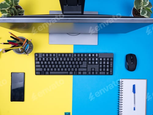 Preview: Flat lay top view of computer monitor over blue background