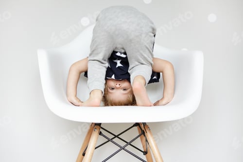Child Playing Upside Down on a Modern Chair