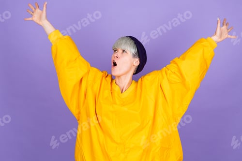 Preview: Stylish european woman on purple background shocked hands up to sides