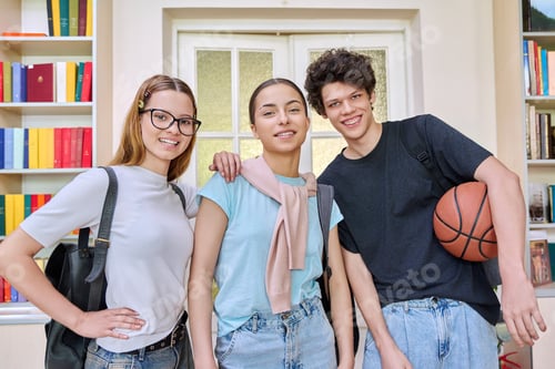 Preview: Three cheerful teenagers students looking at camera inside school campus