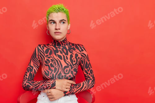 Preview: Horizontal shot of thoughtful hipster girl has bright dyed green short hair looks with pensive expre