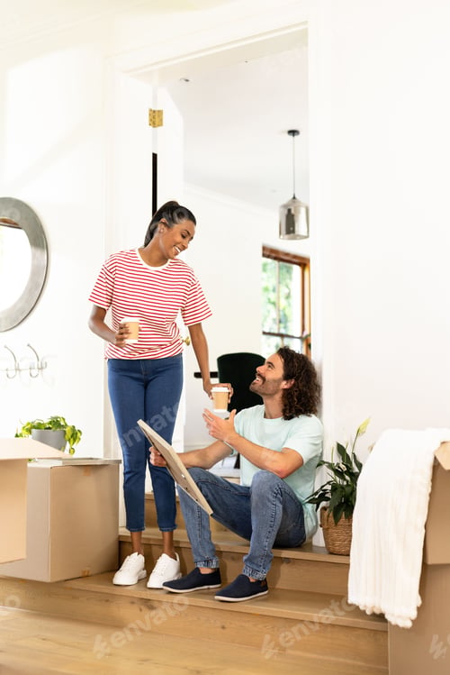 Aperçu: Young couple unpacking boxes at new home, sharing coffee and smiling warmly