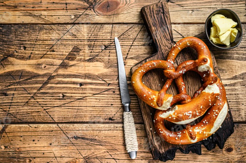 Preview: Baked pretzels with sea salt on a rustic wooden cutting board. Wooden background.