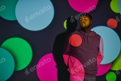 Preview: handsome man with hands behind back and closed eyes in digital projector lights, fashion concept
