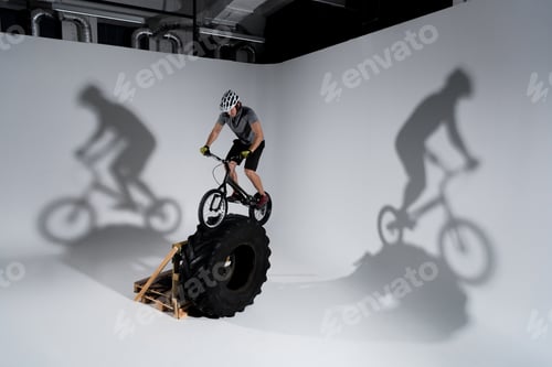Preview: young athletic trial cyclist balancing on tractor wheel