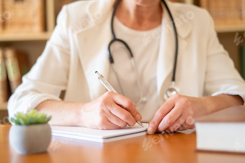 Preview: Healthcare professional sitting at a desk and writing on a notepad